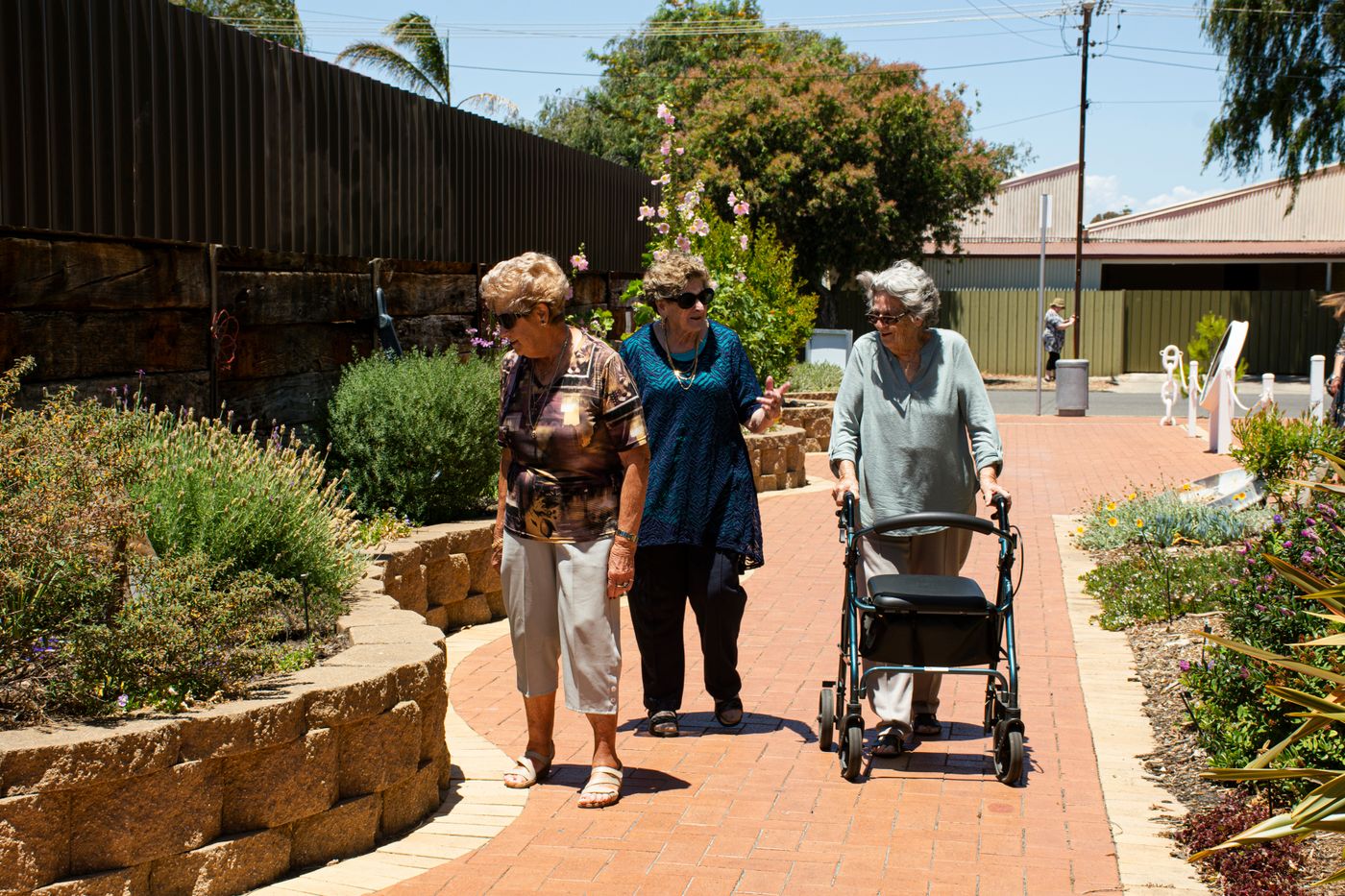 Three senior women enjoying a mindful walk along a park path — tai chi walking practised outdoors
